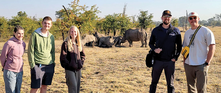 Zambian team members and a family of rhinoceroses at Mosi-ao-Tunya