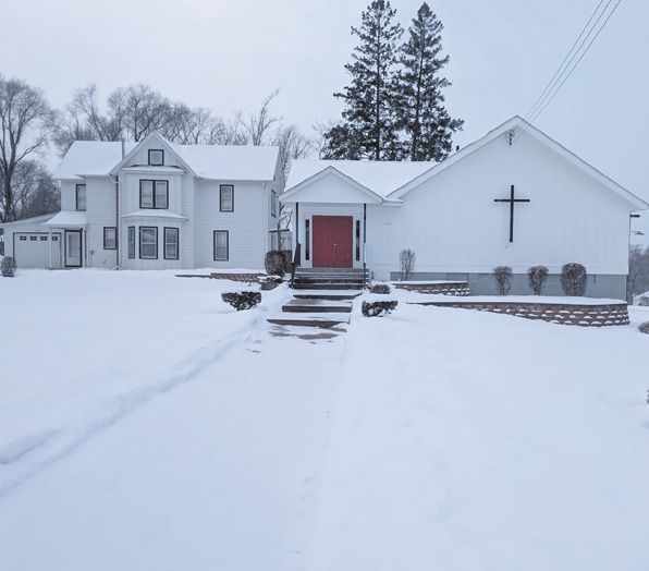 A white church with a red door and a cross on top. The church is surrounded by snow.

AI generated content
